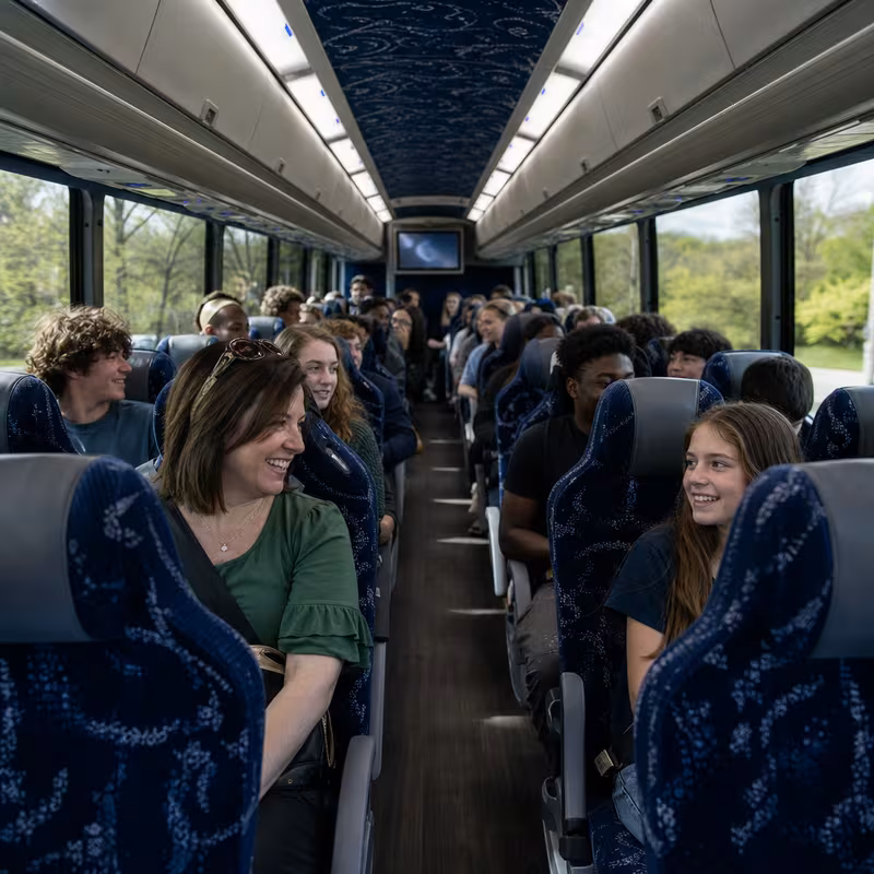 Group boarding a white charter bus for School Transportation transportation in Colorado Springs