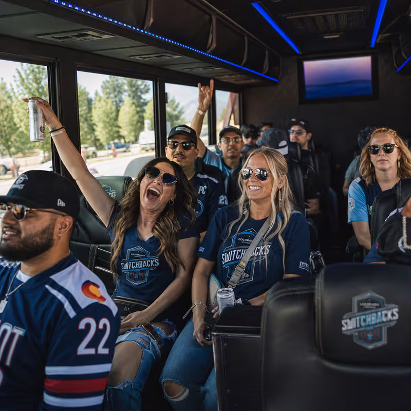 Group boarding a white charter bus for Sporting Event Transportation transportation in Colorado Springs